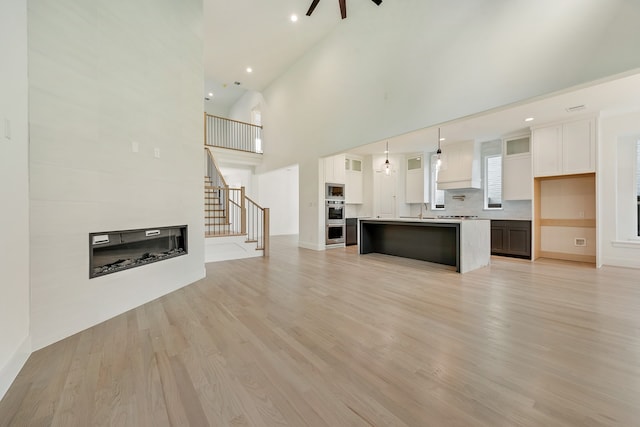 unfurnished living room with a large fireplace, light hardwood / wood-style floors, and a high ceiling