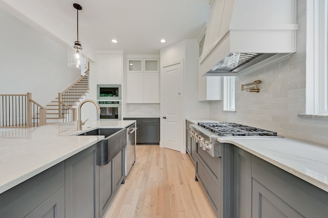 kitchen featuring pendant lighting, appliances with stainless steel finishes, gray cabinetry, premium range hood, and white cabinets