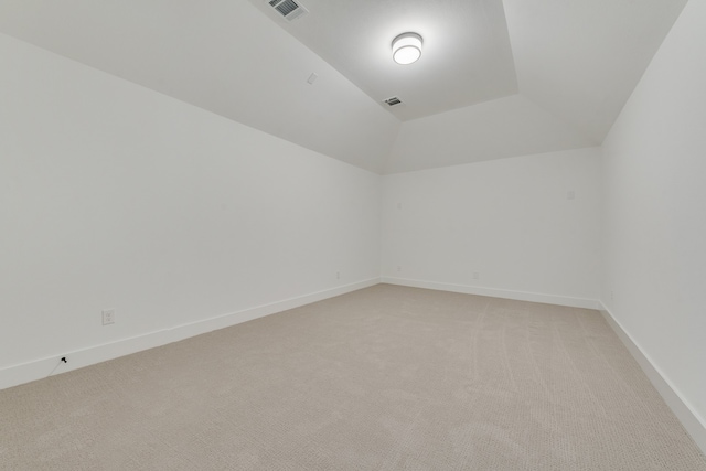 spare room with light carpet and vaulted ceiling