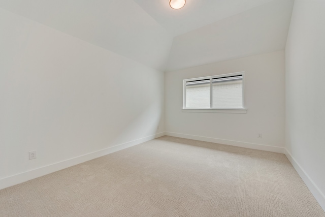 unfurnished room featuring light colored carpet and lofted ceiling