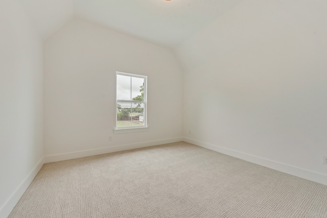 unfurnished room featuring lofted ceiling and light carpet