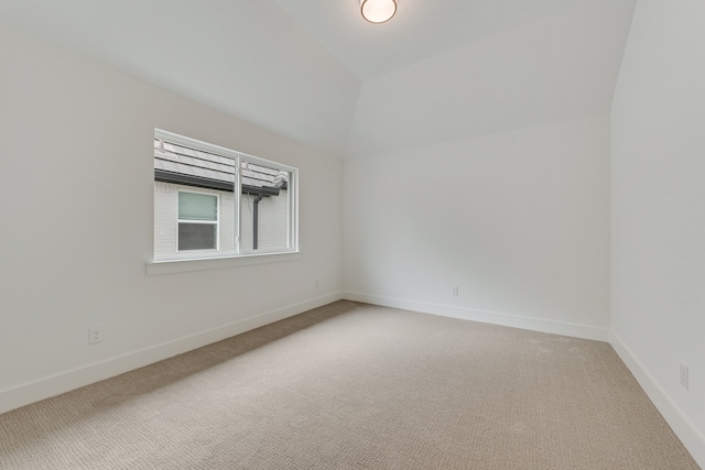 carpeted spare room featuring vaulted ceiling