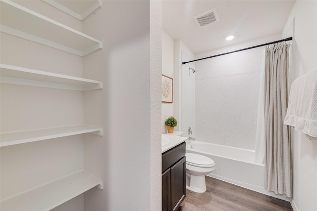 bathroom featuring toilet, wood finished floors, vanity, visible vents, and shower / bath combination with curtain