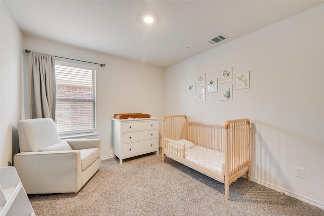 bedroom featuring visible vents, light carpet, baseboards, and a crib