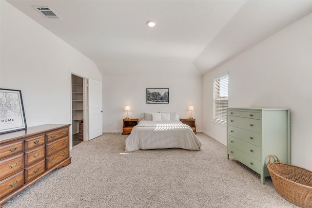 bedroom with a walk in closet, lofted ceiling, light colored carpet, visible vents, and baseboards