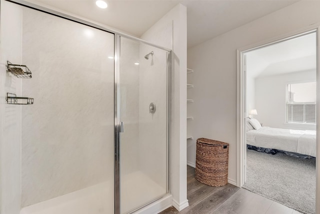 bathroom with a shower stall, baseboards, wood finished floors, and ensuite bathroom