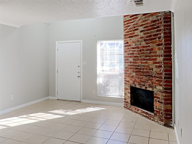 unfurnished living room featuring a textured ceiling, a brick fireplace, and light tile patterned floors