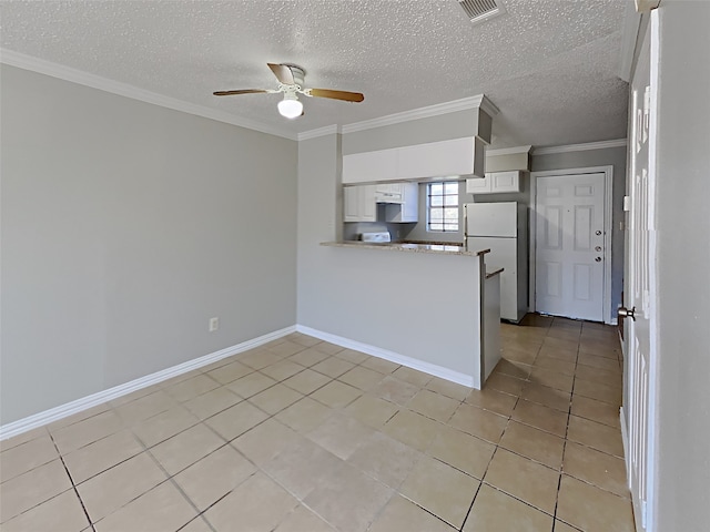 kitchen featuring white cabinets, ornamental molding, light tile patterned floors, white fridge, and kitchen peninsula