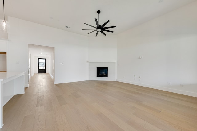 unfurnished living room with light wood-type flooring, a brick fireplace, and ceiling fan