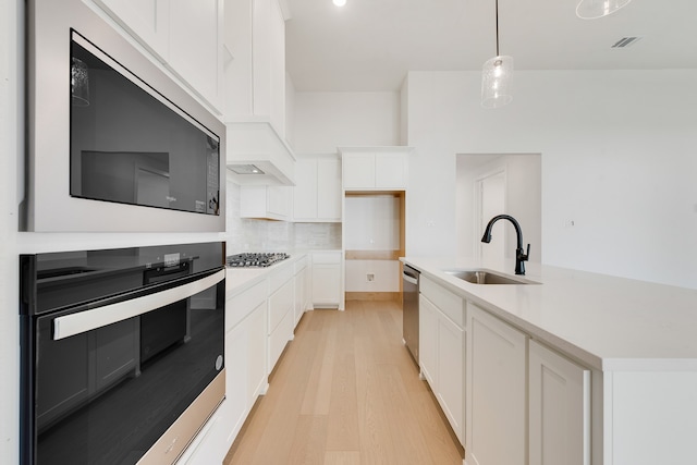 kitchen with white cabinetry, sink, light hardwood / wood-style flooring, decorative backsplash, and appliances with stainless steel finishes