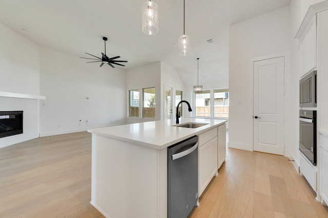 kitchen featuring an island with sink, sink, white cabinets, black appliances, and light hardwood / wood-style flooring