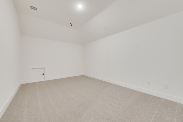 spare room with light colored carpet and lofted ceiling