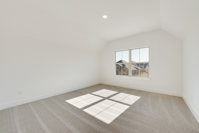 additional living space with vaulted ceiling and light carpet