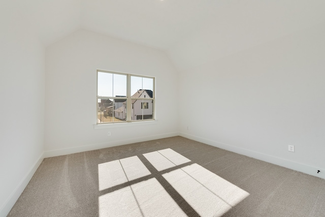 carpeted empty room with vaulted ceiling