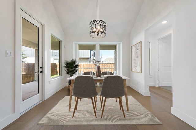 dining room featuring a chandelier, wood-type flooring, and lofted ceiling