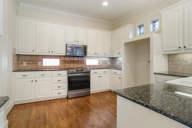 kitchen featuring white cabinetry, stainless steel appliances, dark stone counters, and tasteful backsplash