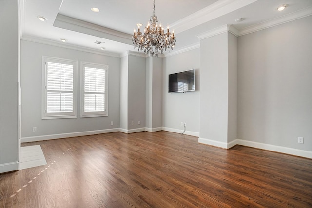 empty room with dark hardwood / wood-style flooring, a raised ceiling, ornamental molding, and an inviting chandelier