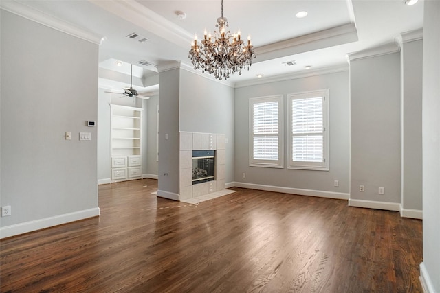 unfurnished living room with dark hardwood / wood-style floors, built in features, a tiled fireplace, and a tray ceiling