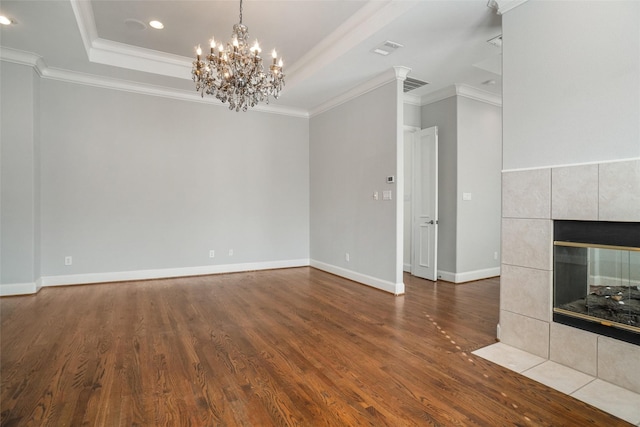 unfurnished living room with a raised ceiling, crown molding, a fireplace, and hardwood / wood-style floors