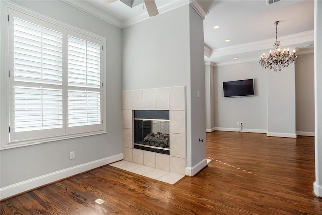 unfurnished living room featuring hardwood / wood-style floors, plenty of natural light, ornamental molding, and a tiled fireplace