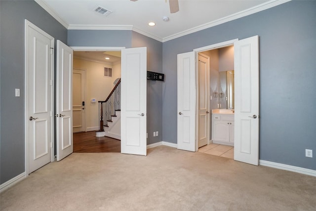 unfurnished bedroom with ensuite bathroom, crown molding, ceiling fan, and light carpet