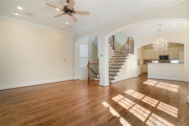 unfurnished living room featuring hardwood / wood-style floors, ceiling fan with notable chandelier, and crown molding