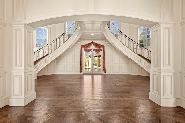 unfurnished living room with a towering ceiling and dark parquet floors