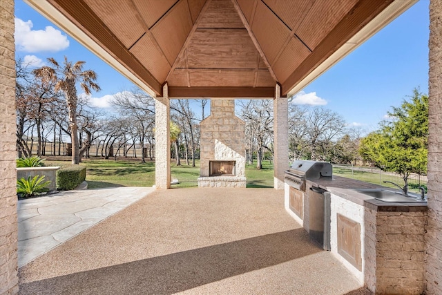 view of patio / terrace with an outdoor kitchen, sink, an outdoor stone fireplace, grilling area, and a gazebo