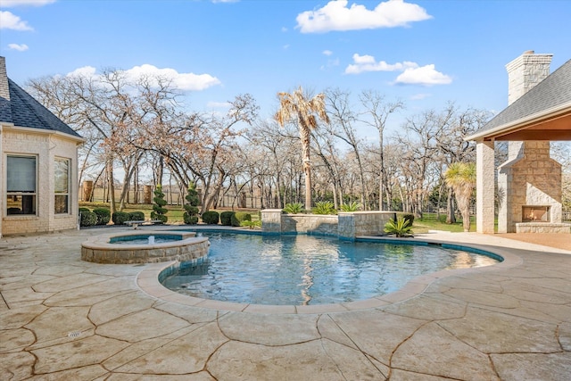 view of swimming pool with an in ground hot tub, pool water feature, a patio, and an outdoor stone fireplace