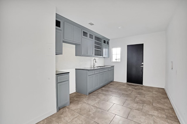 kitchen featuring tasteful backsplash, gray cabinetry, and sink