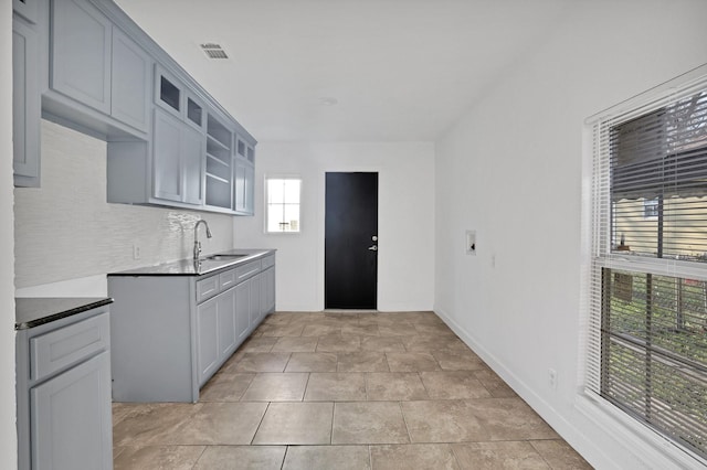 kitchen featuring light tile patterned flooring, gray cabinetry, and sink