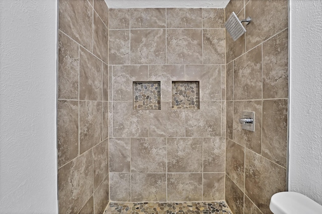 bathroom with tiled shower and toilet