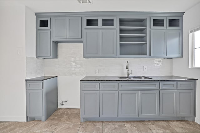 kitchen with gray cabinetry, backsplash, and sink