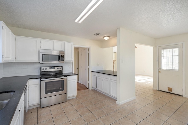 kitchen featuring white cabinets, appliances with stainless steel finishes, a textured ceiling, and decorative backsplash