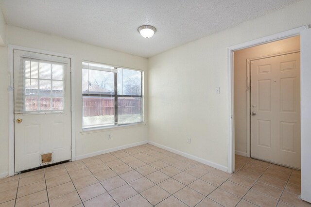 tiled empty room featuring a textured ceiling