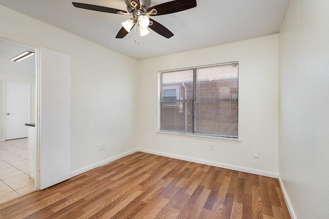 unfurnished room with ceiling fan, a textured ceiling, and light wood-type flooring