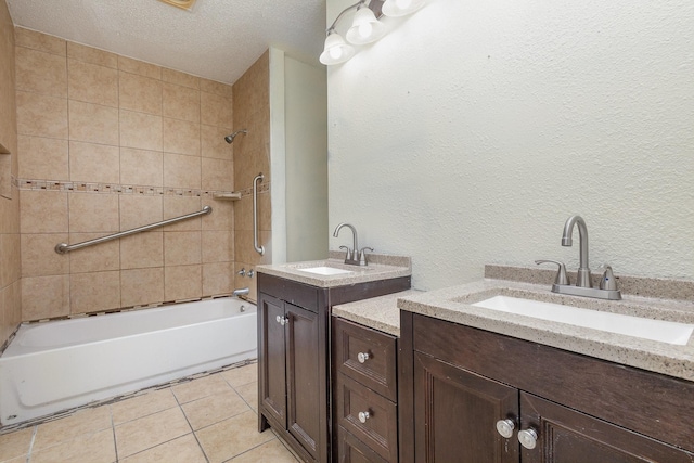 bathroom featuring vanity, a textured ceiling, tile patterned floors, and tiled shower / bath