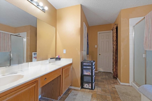 bathroom with a shower with door, vanity, and a textured ceiling