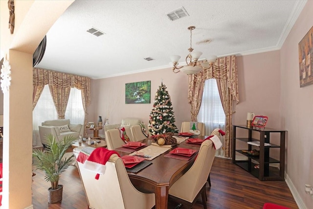 dining space featuring a textured ceiling, dark hardwood / wood-style flooring, crown molding, and an inviting chandelier