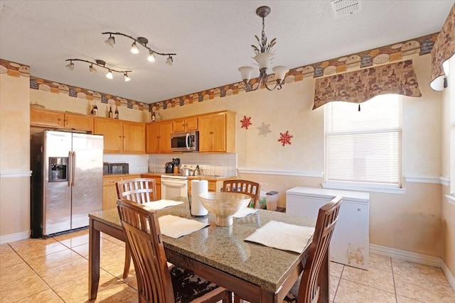 tiled dining room featuring a textured ceiling and an inviting chandelier