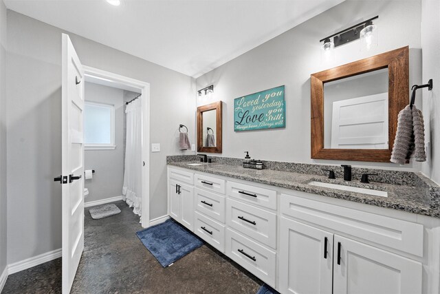 bathroom with vanity, toilet, and concrete floors