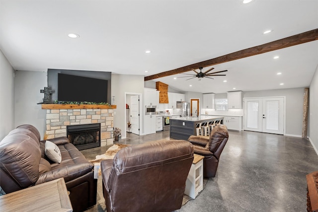 living room with ceiling fan, lofted ceiling with beams, and a stone fireplace