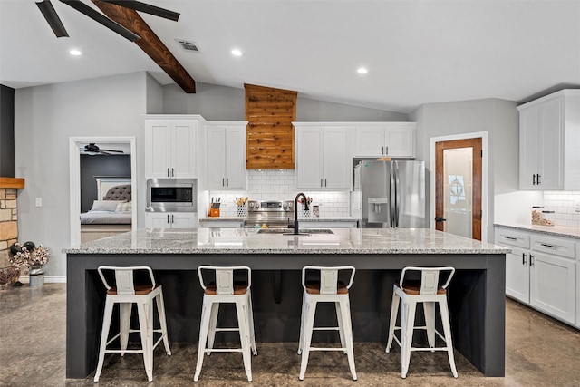 kitchen featuring a center island with sink, white cabinets, sink, appliances with stainless steel finishes, and tasteful backsplash