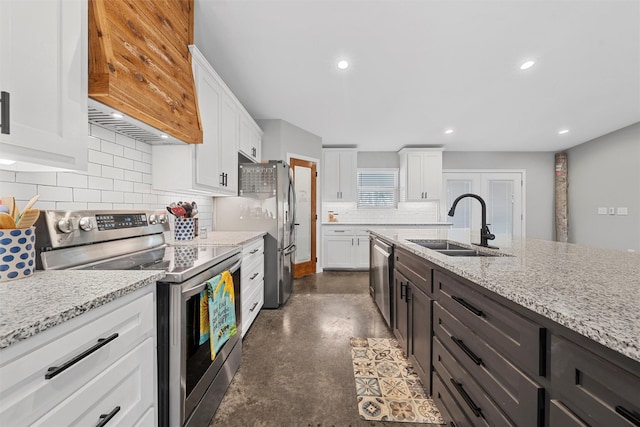 kitchen with light stone countertops, sink, stainless steel appliances, premium range hood, and white cabinets