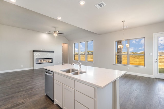 kitchen featuring stainless steel dishwasher, a kitchen island with sink, sink, pendant lighting, and white cabinetry