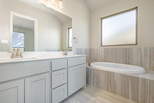 bathroom featuring tile patterned flooring, vanity, a healthy amount of sunlight, and vaulted ceiling