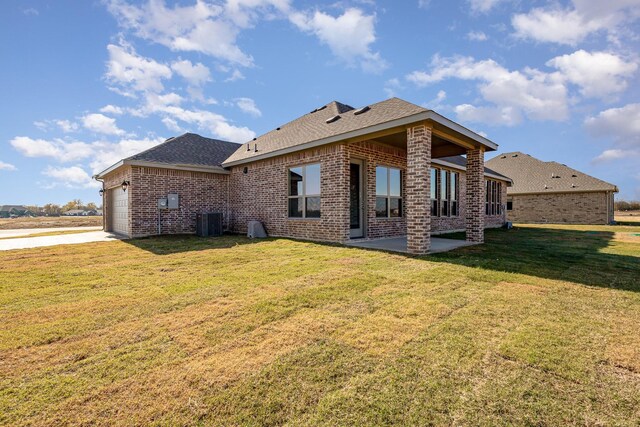 back of house featuring a lawn, a garage, and central AC