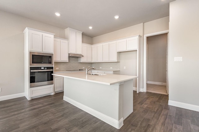 kitchen featuring black appliances, white cabinets, sink, and an island with sink