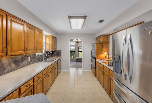 kitchen featuring sink, decorative backsplash, a notable chandelier, light tile patterned flooring, and stainless steel appliances