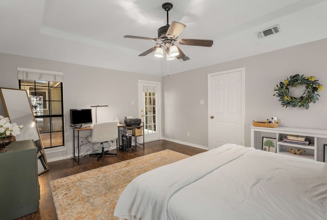 bedroom with a raised ceiling, ceiling fan, and dark hardwood / wood-style flooring